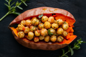 Oven-baked sweet potato topped with spiced chickpeas, tahini drizzle, and fresh herbs.