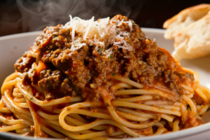 Plate of spaghetti topped with rich, slow-cooked Bolognese sauce and garnished with fresh basil and Parmesan cheese.