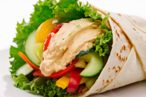 Whole wheat wrap filled with creamy hummus, fresh cucumbers, bell peppers, carrots, and leafy greens.