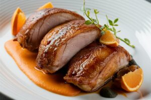 Tender duck breast served with a sweet and tangy orange glaze, garnished with fresh herbs.