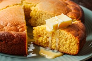 Golden, moist cornbread served with a pat of melted butter on top.