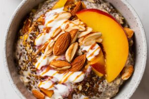 Overnight chia oats topped with fresh peach slices and chopped almonds, served in a jar.