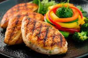 Grilled chicken breast served with a side of steamed vegetables, including broccoli and carrots.