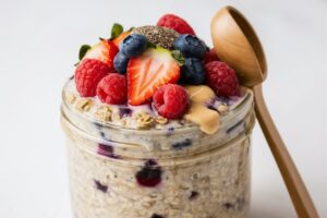 Overnight oats in a jar topped with fresh fruits, nuts, and a drizzle of honey.